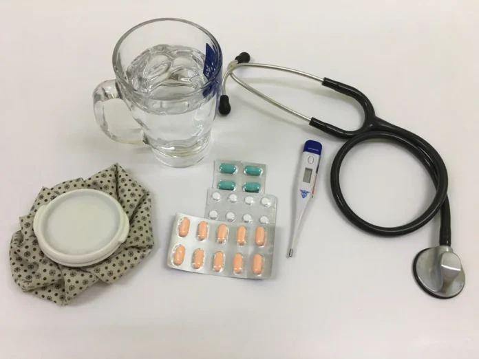 natural alternatives to bipolar medication - Glass of water with medicines, thermometer, stethoscope and icebag.